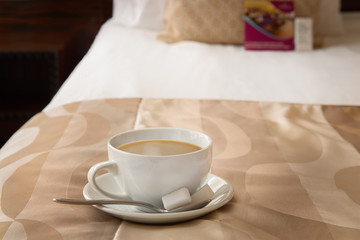 A Cup of coffee on the bed in the hotel room