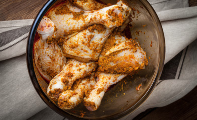 Marinated chicken drumsticks in a glass bowl.