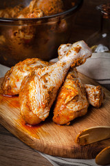 Marinated chicken drumsticks on a wooden chopping board.