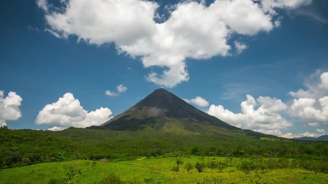 Time lapse of the volcano of Arenal with green meadow at sunny day. Costa Rica
