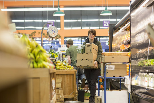 Female worker carrying boxes while working at supermarket