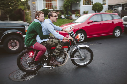 Woman sitting with boyfriend riding motorcycle on road