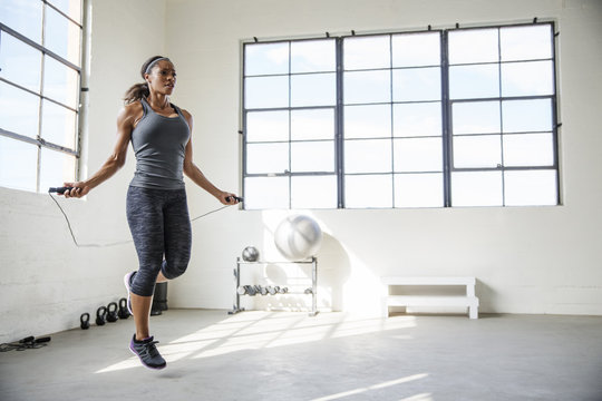 Female athlete skipping with jumping rope in gym