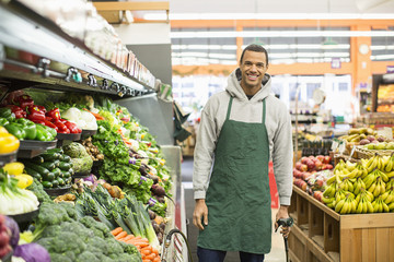 Portrait of smiling worker standing by shelves at supermarket