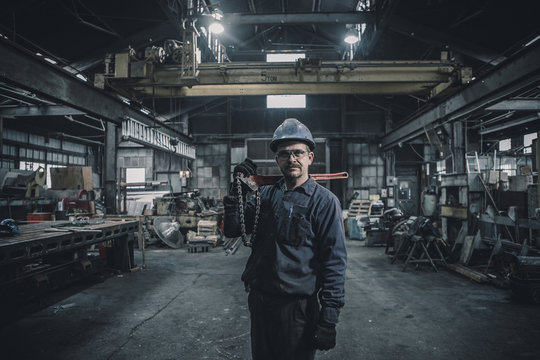 Portrait of worker carrying work tool while standing in factory