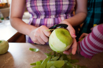 Woman peeling apple at kitchen counter