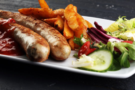 grilled sausages and potatoes and salad