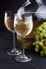 Bottle and glass of white wine, grape on wooden table
