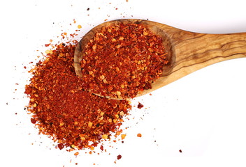 pile crushed red cayenne pepper, dried chili flakes, seeds and wooden spoon isolated on white...
