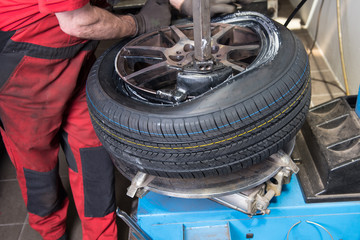 Mann montiert neuen Reifen auf einer Felge in der Werkstatt