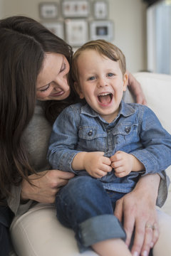 Portrait of boy screaming while sitting with mother at home