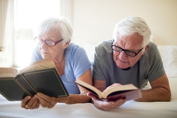 Senior couple reading books on bed