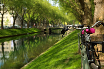 Fototapeta na wymiar Bicycle in the park near the river on bright sunny summer green background