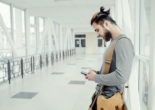 Side View Of Man Using Mobile Phone While Standing In Corridor