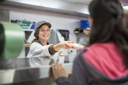 Smiling worker giving packet to customer at supermarket