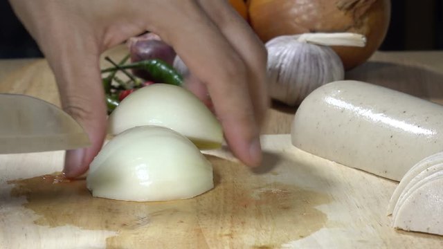 Vegetables (onions being cut into pieces) on wooden floor