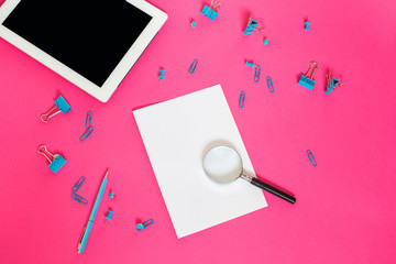 Stationery on a pink background. Paper clips and binders