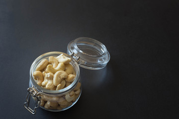 Cashew nuts in a jar on the dark stone table background.