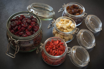 Healthy dried fruits, seeds and nuts on dark stone table background.