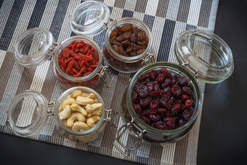 Healthy dried fruits, seeds and nuts on dark stone table background.