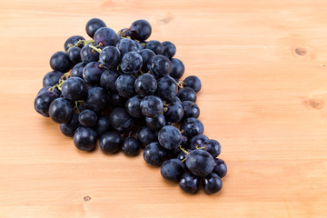 Bunch of dark ripe grapes on an oak natural wood table