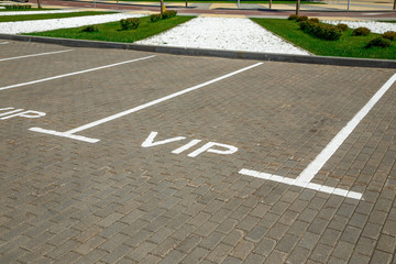 Empty parking space separated by white stripes markings. The parking place has an inscription VIP