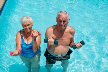 Senior couple exercising with dumbbells in the pool