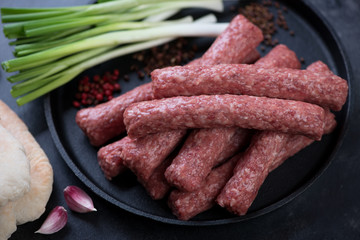 Close-up of raw fresh cevapi sausages in a frying pan, horizontal shot