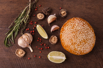 Garlic, spices and bun with sesame seeds on the wooden background. Top view.