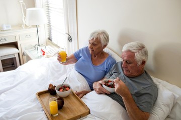 Senior couple having breakfast on bed