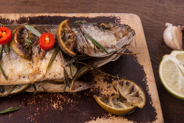 Head fish close-up with filling, stuffed with vegetables and lime on cutting board