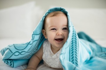 Cute baby girl under the blanket on bed