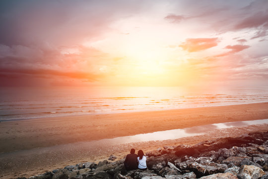 future together concept. landscape of couple lover people sitting together on the beach looking forward to the sea with sunset light.