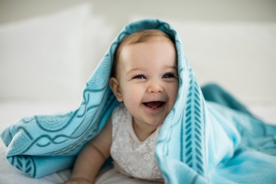 Cute Baby Girl Under The Blanket On Bed