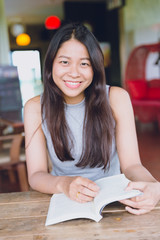 Enjoy relax times with reading book, Asian women Thai teen smile with book in coffee shop