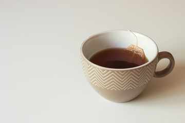 Brown ceramic cup with black tea and paper tea bags