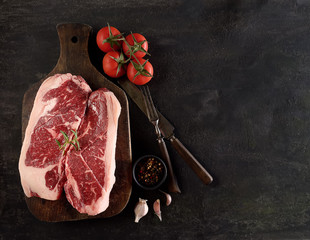 Raw marbled beef on a cutting board. On a black background
