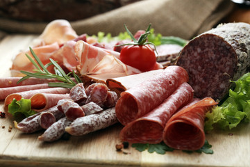 Food tray with delicious salami, pieces of sliced ham, sausage, tomatoes, salad and vegetable - Meat platter with selection