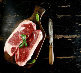 Raw marbled beef on a cutting board. On a black background
