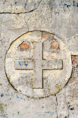 Cross symbol on a old, ruined wall