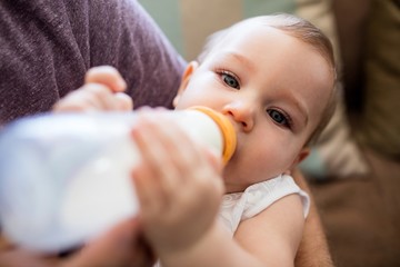 Father feeding milk to baby girl