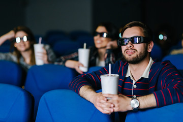 Young man smiling and watching a 3D movie at the cinema