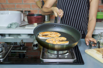 Cropped of hands coocking fish in luxury kitchen