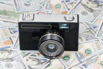 Old retro camera on dollars spread out on a table, close-up