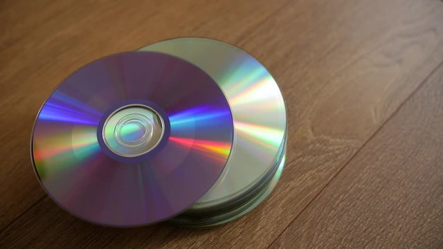 Closeup of a stack compact discs on wooden floor background. Cd falling from the top, slow-motion.
