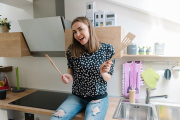 Cute girl playing air drums in her new kitchen