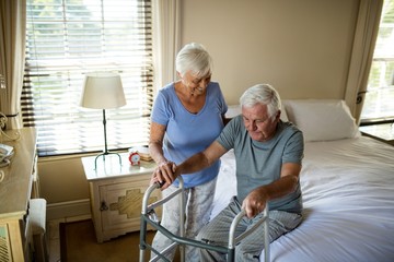 Senior woman helping man to walk with a walker