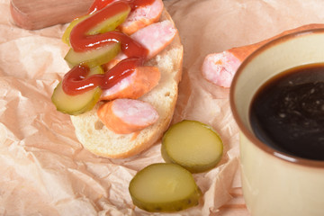 Quick sandwich with cucumber sausage and ketchup on paper