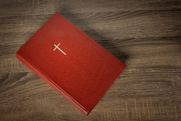 Red bible with cross on cover, wooden table background