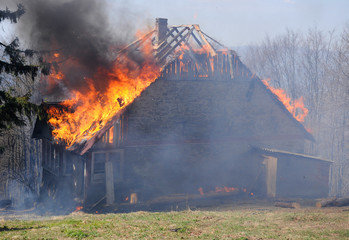 Burning wooden house. Burning fire flame on wooden house roof. Building covered by flame.